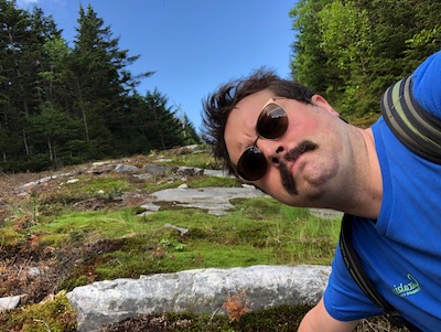 Zach's photo with a mustache on a mountain